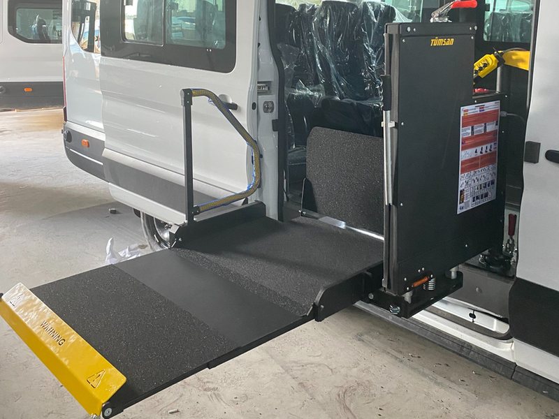 Beyaz minibüsün yan kapısında açılmış Tümsan döner tipi lift